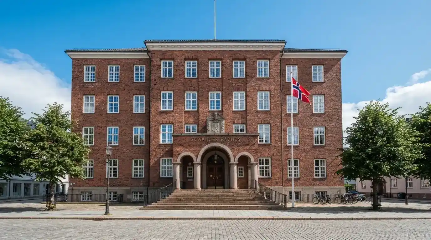 Offentlig kontorbygning i rødt murstein i en norsk by, med et flagg ved inngangen og blå himmel